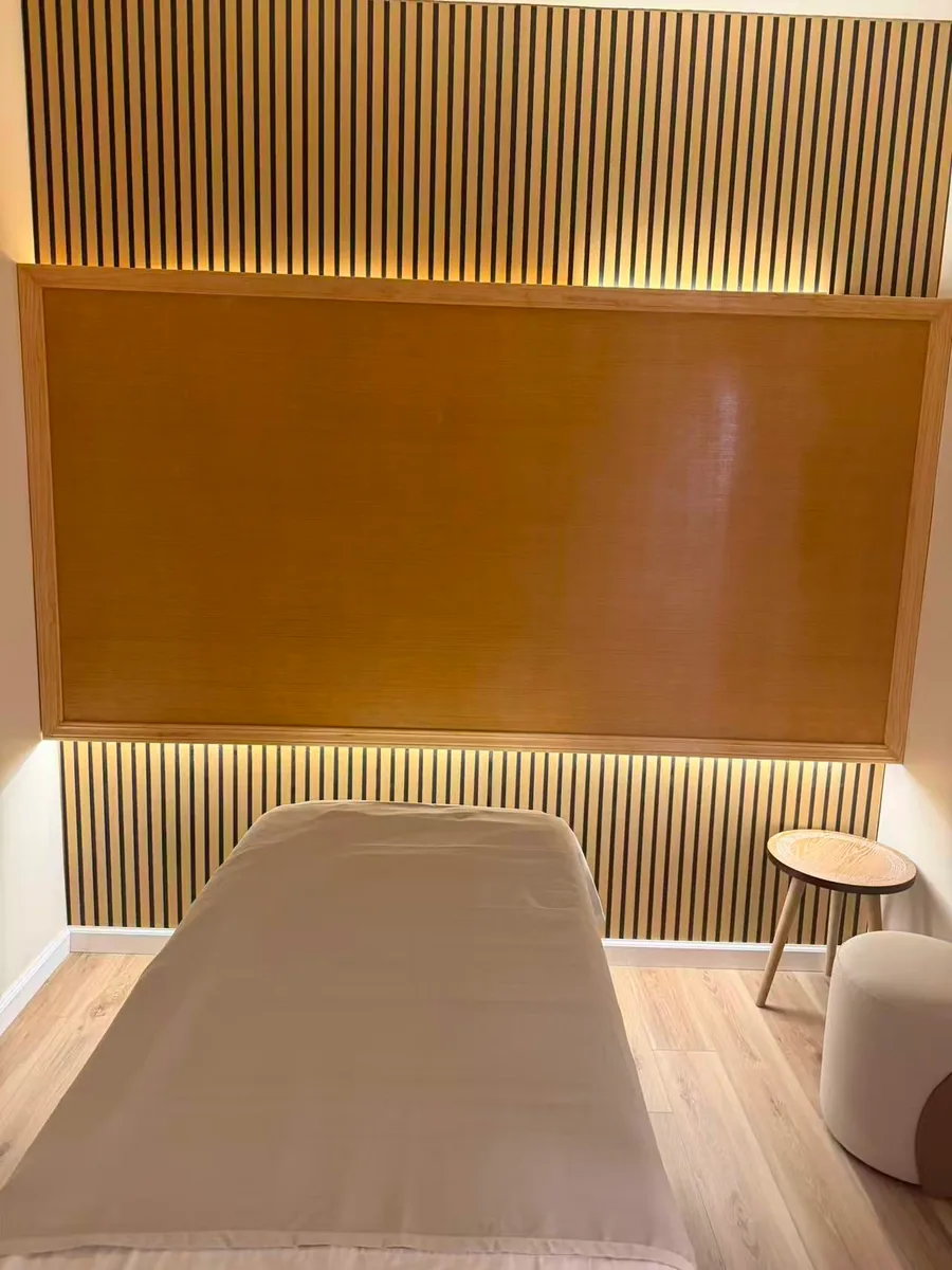 A single treatment room at Diamond Massage with a slatted wood wall, backlit amber panel and a freshly made table