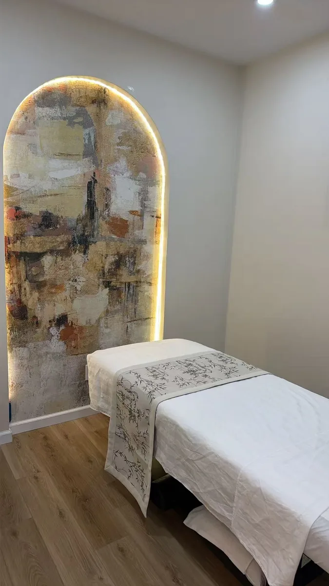 treatment room at Diamond Massage, a made table beside a backlit arched art niche